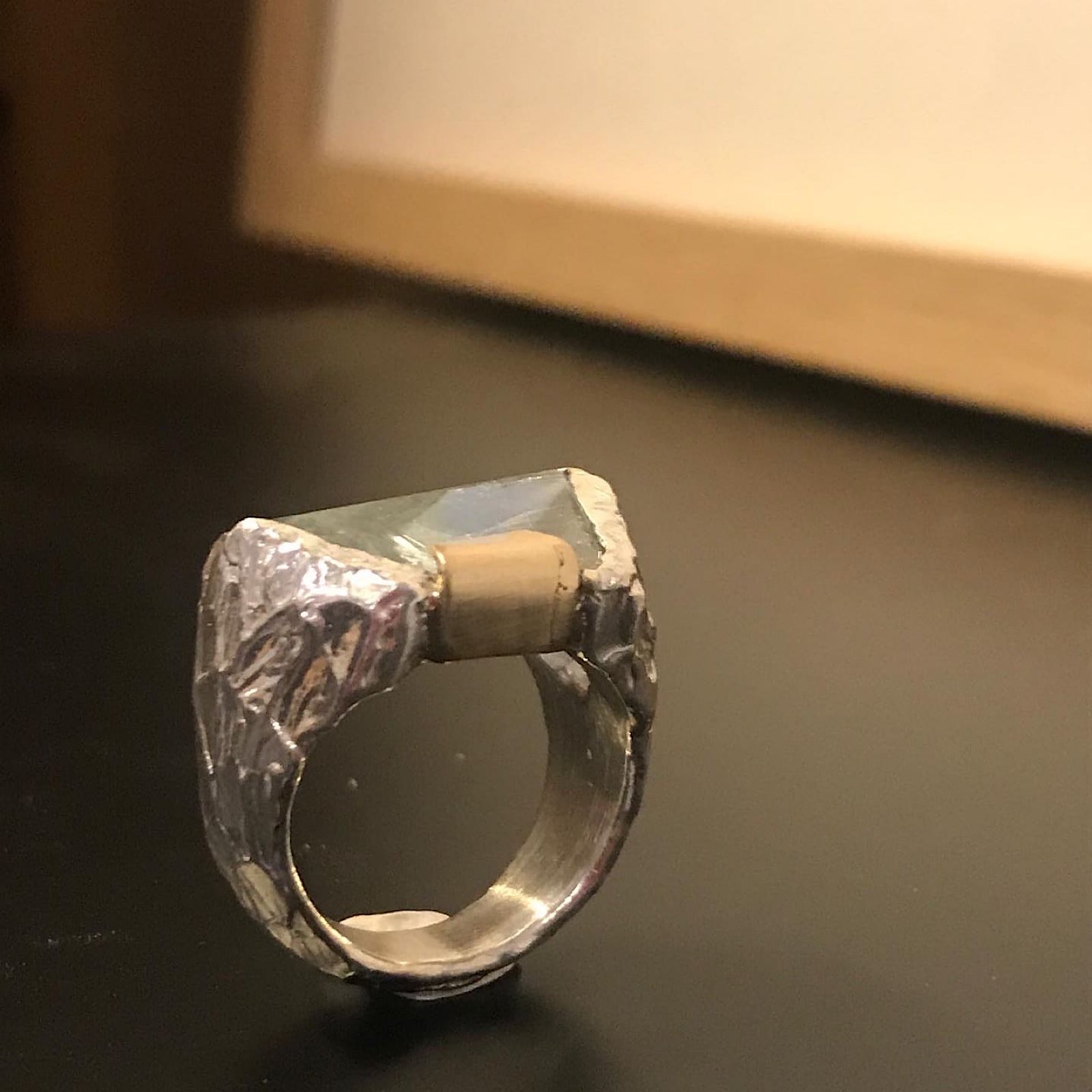 Anillo con piedra azul clara sobre banda de plata esculpida